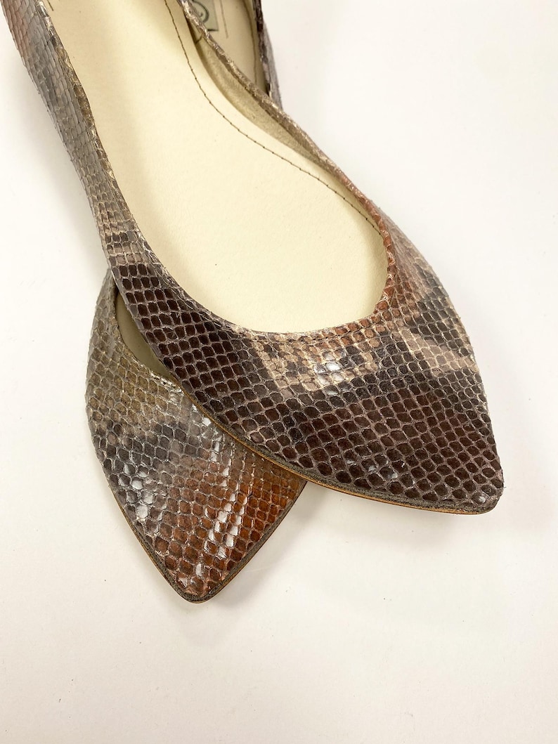 Peut inclure: Une paire de ballerines &agrave; bout pointu avec un motif peau de serpent dans les tons marron, beige et gris. Les chaussures ont un petit talon et une semelle int&eacute;rieure en cuir. Les ballerines sont con&ccedil;ues pour un ajustement confortable et un look &eacute;l&eacute;gant.