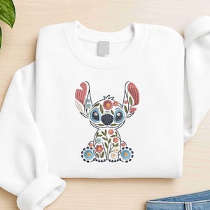 Könnte beinhalten: Weißes Sweatshirt mit einem gestickten floralen Stitch-Design. Das Design umfasst blaue, rote und gelbe Blumen, wobei die Ohren und der Körper von Stitch mit aufwendigen floralen Mustern verziert sind. Das Sweatshirt hat einen Rundhalsausschnitt und lange Ärmel.