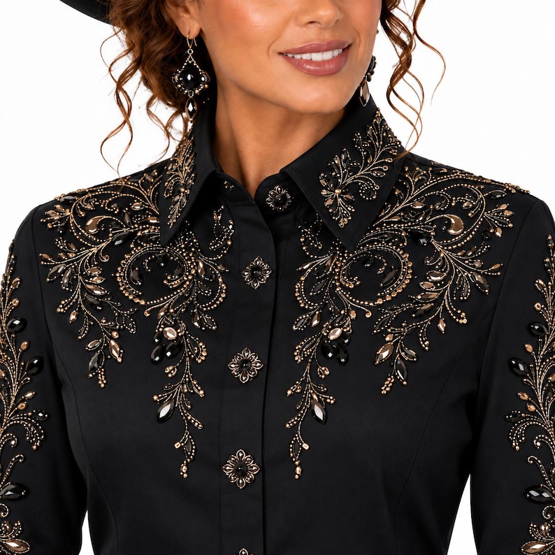 Puede incluir: Una camisa negra de manga larga con botones, que presenta intrincados bordados dorados y adornos negros en forma de l&aacute;grima en el pecho, los hombros y el cuello. La camisa incluye botones decorativos en forma de flor a lo largo de la tapeta frontal.