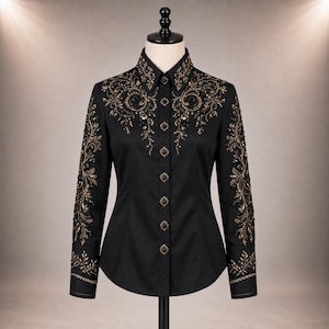 Puede incluir: Una camisa negra de manga larga con botones, que presenta intrincados bordados en dorado y negro a lo largo del cuello, los hombros y las mangas. La camisa incluye botones cuadrados decorativos en la parte frontal y adornos florales.