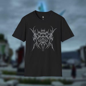Op de afbeelding: Zwart t-shirt met een gestileerd grijs grafisch ontwerp. Het ontwerp is een abstracte, symmetrische rangschikking van scherpe, hoekige vormen. Het t-shirt heeft korte mouwen en een ronde hals, geschikt voor casual wear.