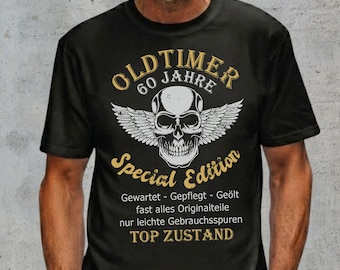 Può includere: Una t-shirt nera a maniche corte con la grafica di un teschio alato. Il testo recita OLD TIMER 60 JAHRE Special Edition, seguito da testo in tedesco: Gewartet - Gepflegt - Geölt, fast alles Originalteile, nur leichte Gebrauchsspuren, TOP ZUSTAND.