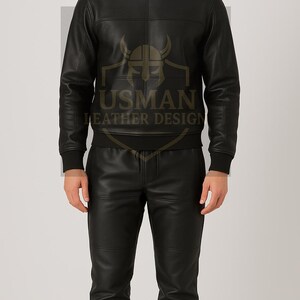 Puede incluir: Conjunto negro de cuero, compuesto por una sudadera y pantalones a juego. La sudadera tiene cuello redondo y diseño de paneles en el pecho. Los pantalones son de corte ajustado. El logo "USMAN LEATHER DESIGN" es visible.