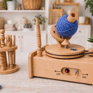 May include: A wooden yarn spinning wheel with a blue yarn ball, a wooden crochet hook holder with various hooks, and a blue knitted item. The spinning wheel has an on/off switch and the word "OFF" is visible.