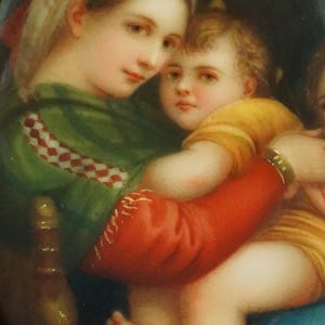 Peut inclure: Peinture ovale représentant une femme en vêtement vert et blanc à motifs, tenant un enfant en chemise jaune et enveloppe rouge. La femme porte un couvre-chef blanc à rayures jaunes. La peinture a une palette de couleurs chaudes.