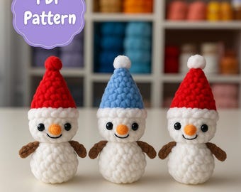 Peut inclure: Trois bonhommes de neige au crochet faits à la main, avec des corps blancs, des bras bruns et des visages souriants. Chaque bonhomme de neige porte un chapeau de couleur différente : rouge, bleu et rouge. L'image comprend le texte "PDF Pattern" dans une bulle violette.