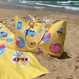 May include: A yellow beach tote bag and matching beach towel with summer-themed stickers. The tote bag has white rope handles and features stickers with phrases like "Sunny Days" and "Relax & Enjoy". The towel has a pineapple wearing sunglasses.