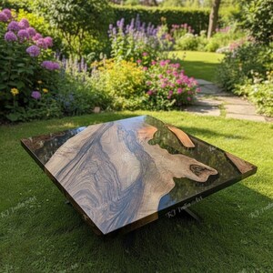 May include: Square wooden coffee table with a dark, glossy epoxy resin top. The table features a natural wood grain pattern with a mix of brown, black, and tan tones. The table is set on a green lawn with a garden in the background.