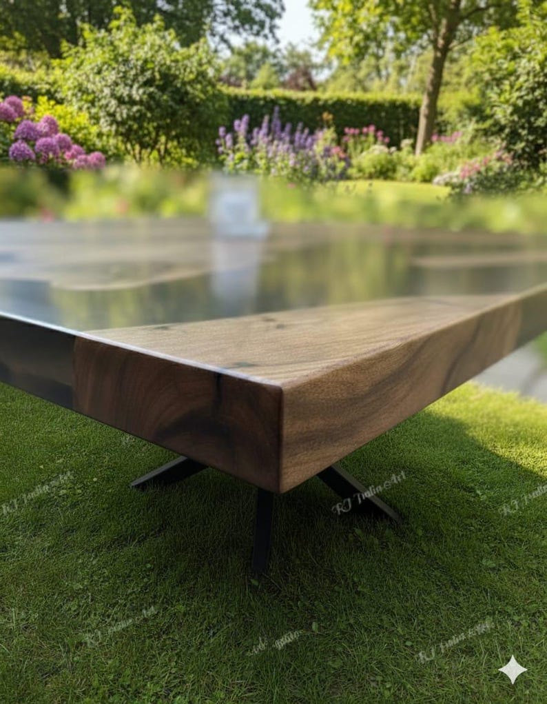 May include: A modern wooden table with a dark finish and a sleek, rectangular design. The table has a natural wood grain and is supported by black metal legs. The table is set on a green lawn with a blurred garden background.