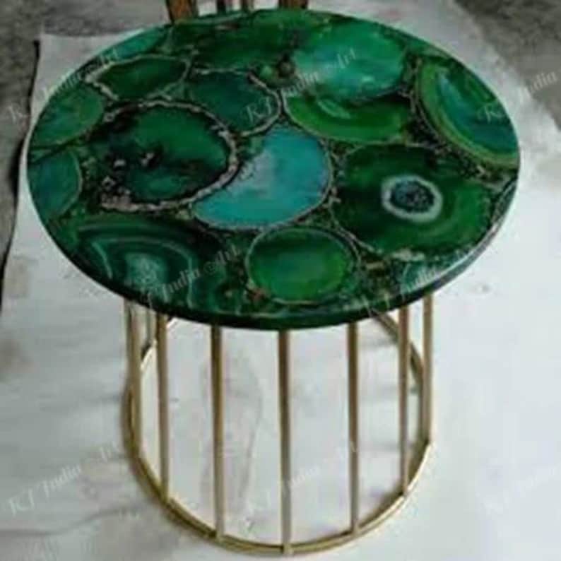 Puede incluir: Una mesa auxiliar redonda con una vibrante tapa de &aacute;gata verde. La superficie presenta un mosaico de rodajas de &aacute;gata verde y turquesa. La mesa tiene una base de metal dorado con barras verticales, creando un aspecto moderno y elegante.