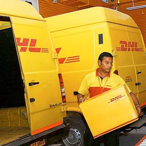 May include: A yellow DHL delivery van with the door open, revealing the interior. A person in a yellow and red uniform is holding a yellow DHL box. The DHL logo is visible on the van and the box.