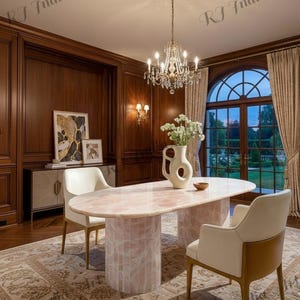 May include: Elegant dining room featuring a pink oval table with a mosaic base, surrounded by cream-colored chairs. A crystal chandelier hangs above, and a large window offers a view of the outdoors. The room has dark wood paneling and a patterned rug.