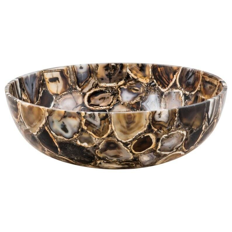 May include: A decorative, oval-shaped bowl crafted from polished agate stone. The bowl features a mosaic pattern of brown, tan, and cream-colored stones, creating a unique and natural design. The bowl is ideal for decorative purposes.
