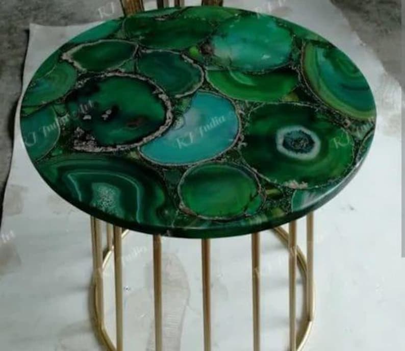 Puede incluir: Una mesa auxiliar redonda con una tapa hecha de rodajas de &aacute;gata verde. El &aacute;gata es una mezcla de tonos verdes oscuros y claros con detalles blancos y marrones. La mesa tiene una base de metal dorado.