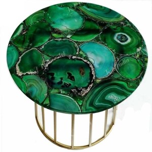 Puede incluir: Mesa auxiliar redonda con tapa de piedra de &aacute;gata verde. La encimera est&aacute; compuesta por varias tonalidades de rodajas de &aacute;gata verde, creando un patr&oacute;n &uacute;nico. La base es de metal color dorado con un dise&ntilde;o curvo.