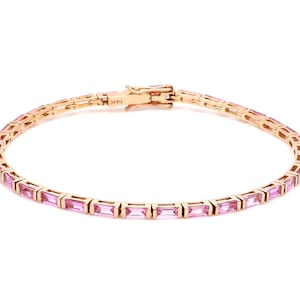 May include: A gold bracelet with pink rectangular gemstones. The bracelet is made of gold and features a series of pink gemstones set in a row. The clasp is visible and marked with "14K".