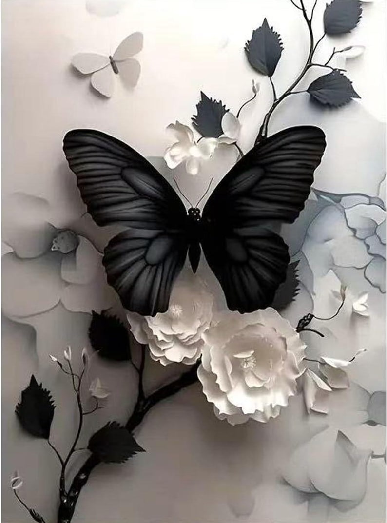 Op de afbeelding: Een grijstinten kunstwerk met een grote zwarte vlinder met gedetailleerde vleugels, geplaatst tussen witte papieren bloemen en bladeren. Een kleinere witte vlinder bevindt zich op de achtergrond, waardoor een gelaagd effect ontstaat.