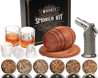 May include: A whiskey smoker kit featuring a black box with gold text, a wooden barrel-shaped smoker on a round base, a grey torch, two glass tumblers with amber liquid, and six metal tins containing wood chips labeled pear, walnut, oak, cherry, apple, and peach.