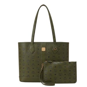 Puede incluir: Un bolso tote de color verde oliva y un estuche de muñeca rectangular a juego. Ambos artículos presentan un patrón de monograma MCM negro repetido, herrajes en tono dorado y una textura lisa con una franja vertical central en el bolso.