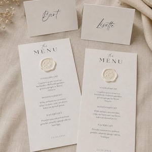 Op de afbeelding: Twee off-white menukaarten en twee bijpassende naamkaartjes met de namen Bart en Lisette. Elk menu bevat de tekst The MENU, een crèmekleurig waszegel met een botanisch ontwerp en een lijst met gerechten in het Nederlands.