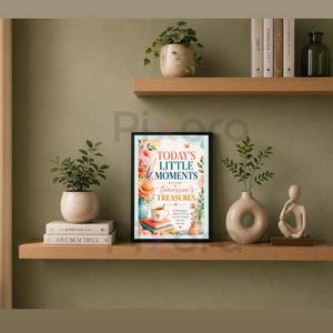 Könnte beinhalten: Ein gerahmter Kunstdruck mit einer Blumenillustration und dem Text "TODAY'S LITTLE MOMENTS BECOME tomorrow's TREASURES." Das Bild zeigt eine Kaffeetasse, gestapelte Bücher und bunte Blumen in einem weichen, künstlerischen Stil.