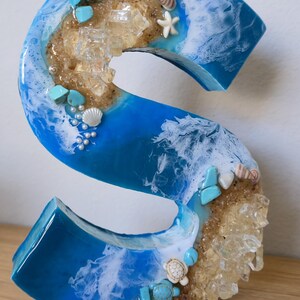 Wolnostojące litery z żywicy oceanicznej z piaskiem kwarcowym w kolorze złotym i muszlami S