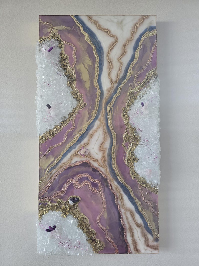 Może przedstawiać: Abstrakcyjna grafika ścienna w stylu geody, w odcieniach fioletu, złota i bieli. Grafika ma teksturowaną powierzchnię z kryształowymi zdobieniami. Prostokątny element jest zamontowany na białej ścianie. Projekt zawiera złote linie.