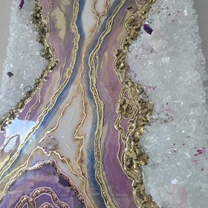 Może przedstawiać: Abstrakcyjne dzieło sztuki z motywem geody w odcieniach fioletu, złota, bieli i błękitu. Obraz ma teksturowaną powierzchnię z kryształowymi akcentami na krawędziach, tworząc unikalną dekorację ścienną.