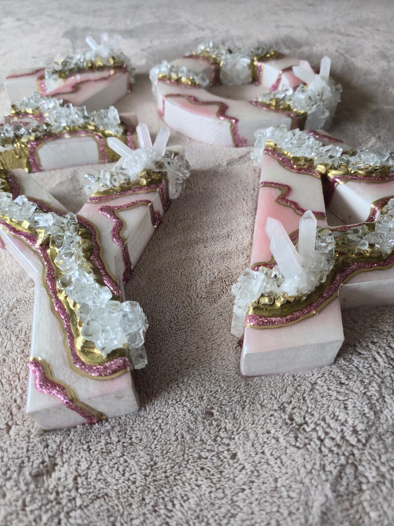 May include: Wooden letters with a pink and gold design, accented with clear crystal clusters. The letters are white with pink and gold accents, and the crystals add a sparkling touch. These decorative letters are perfect for home decor or special events.