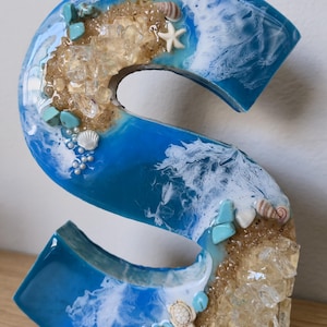 Wolnostojące litery z żywicy oceanicznej z piaskiem kwarcowym w kolorze złotym i muszlami zdjęcie 1