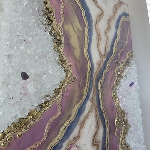 Może przedstawiać: Abstrakcyjna grafika ścienna z motywem geody w odcieniach fioletu, złota, bieli i błękitu. Grafika zawiera elementy krystaliczne i złote akcenty, tworząc warstwową fakturę. Praca jest zamontowana na kwadratowym pł&oacute;tnie.