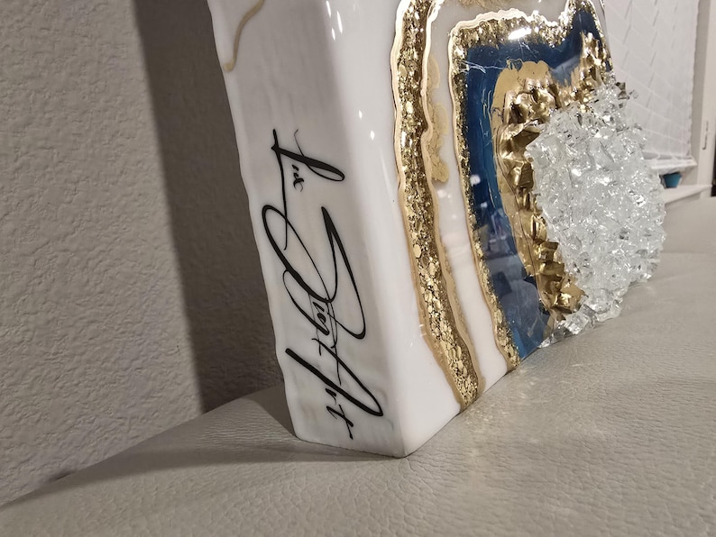 May include: White, rectangular art piece with a geode design. The geode features gold, blue, and clear crystal accents. The side of the piece has black cursive text that reads "Liz Joy Art".