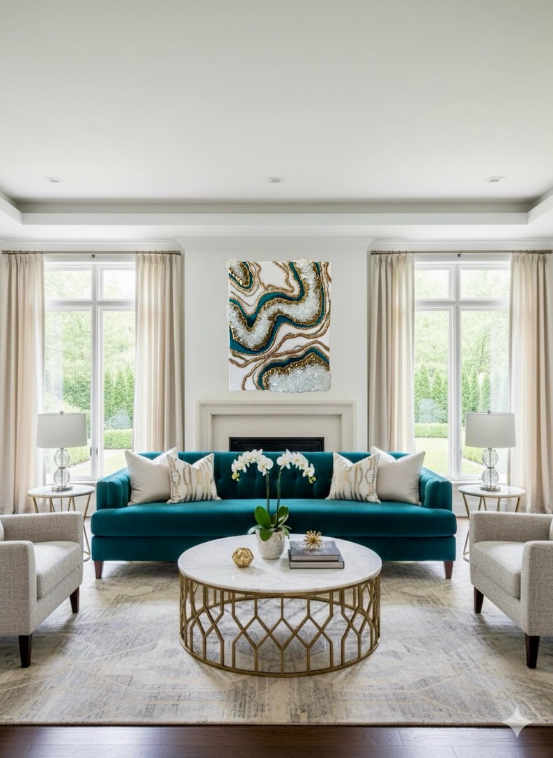 May include: A living room with a teal sofa, two armchairs, and a marble-topped coffee table. A large abstract painting with teal, gold, and white accents hangs above the fireplace. The room has neutral-colored curtains and a patterned rug.