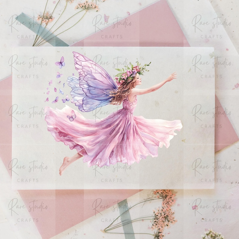 Puede incluir: Ilustraci&oacute;n en acuarela de un hada con un vestido rosa fluido y grandes alas detalladas en tonos morados y azules. El hada tiene una corona floral y est&aacute; rodeada de mariposas. La imagen tiene el texto "Rare Studio Crafts".