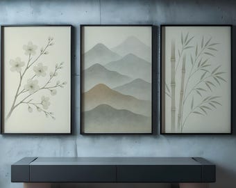 May include: Three framed art prints with a minimalist aesthetic. The prints feature a floral branch, a mountain range, and bamboo stalks, all in muted tones. The frames are black, and the artwork is displayed on a neutral background.