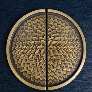 May include: A pair of brass-toned cabinet pulls. Each pull is a half-circle with a floral pattern, and they are set against a dark blue background. The pulls have a detailed, textured design.