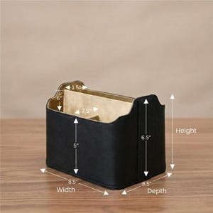 May include: A black leather desk organizer with a beige interior. The organizer is 8.5 inches wide, 6.5 inches deep, and 6.5 inches tall. It has multiple compartments and is designed to hold office supplies.