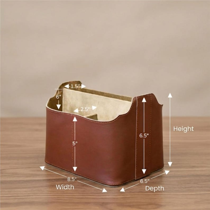 May include: A brown leather desk organiser with multiple compartments. The organiser is 21.6 cm wide, 16.5 cm deep, and 16.5 cm tall. The interior has a beige lining and is divided into sections for storage.