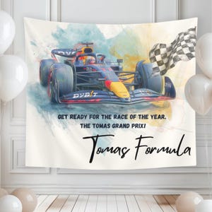 May include: A rectangular fabric wall hanging featuring a watercolor-style illustration of a dark blue and yellow Formula 1 race car and a checkered flag. Text reads: GET READY FOR THE RACE OF THE YEAR. THE TOMAS GRAND PRIX! Tomas Formula.