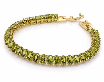 Peut inclure: Un bracelet tennis doré composé d'une rangée continue de pierres précieuses ovales de couleur vert péridot, serties dans des griffes métalliques individuelles. Le bracelet est doté d'un fermoir à cliquet sécurisé avec un loquet de sécurité.