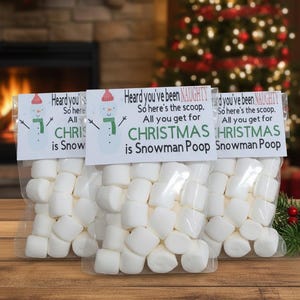 May include: Three clear cellophane bags filled with white marshmallows. Each bag has a label with a snowman graphic and the text "Heard you've been NAUGHTY. So here's the scoop. All you get for CHRISTMAS is Snowman Poop."