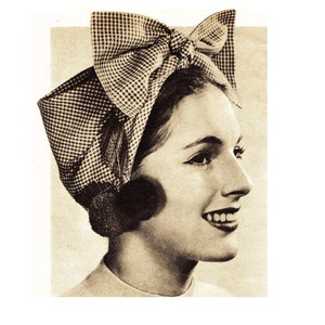 May include: A woman wearing a black and white gingham turban with a large bow on top.