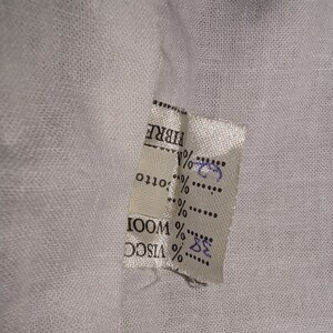 May include: White fabric label with black text that reads "FIBRE" and lists the percentages of different materials: 32% VISCO, 68% WOOL, 0% OTTO.