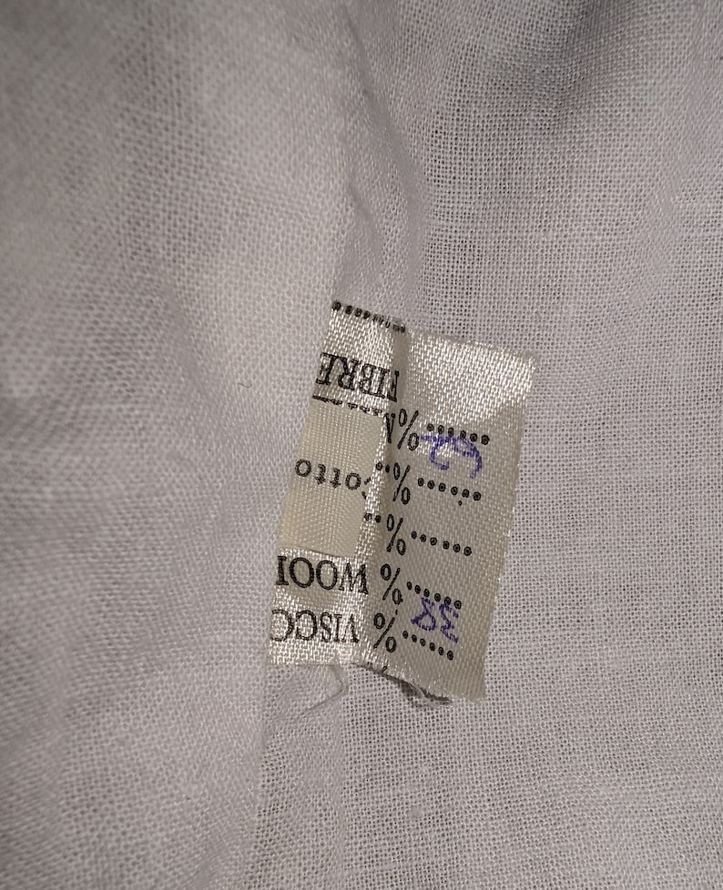 May include: White fabric label with black text that reads "FIBRE" and lists the percentages of different materials: 32% VISCO, 68% WOOL, 0% OTTO.