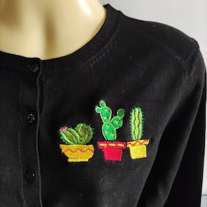 May include: Black cardigan with three embroidered cacti in yellow, red, and green pots.