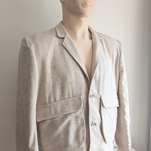 May include: A light beige linen blazer with two large patch pockets and button closures.
