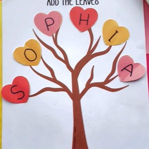 May include: A handmade craft project featuring a brown tree with heart-shaped leaves spelling "SOPHIA". The leaves are in shades of pink, yellow, and red. The phrase "ADD THE LEAVES" is written at the top. The background includes pink and orange paper.