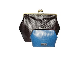 Könnte beinhalten: Zwei Geldbörsen mit Schnappverschluss. Die größere Geldbörse ist dunkelbraun mit einer gewebten Textur und einem goldfarbenen Verschluss. Die kleinere Geldbörse ist blau mit glatter Textur und einem silberfarbenen Etikett. Beide Geldbörsen haben eine sechseckige Form.