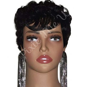May include: A mannequin head with a short, black, curly wig and long, dangling silver earrings. The mannequin has full lips, long eyelashes, and the text "Pixie Me U" is visible on the face.