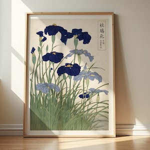 May include: A framed print featuring a Japanese woodblock print of irises. The artwork showcases vibrant blue and light blue irises with yellow centers, set against a beige background. The irises are surrounded by green grass.